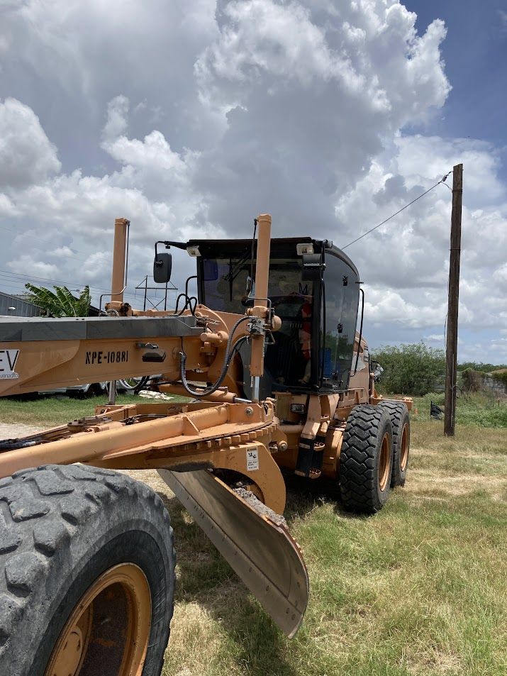 Motor grader spreading and leveling road base in Brownsville, Texas